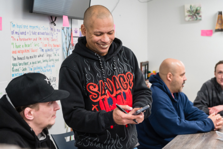 Man looking on his phone showing another man